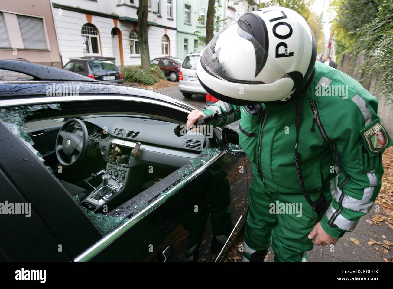 Police officer inspecting a car broken into by thieves who have stolen a radio and navigation system, Essen Stock Photo