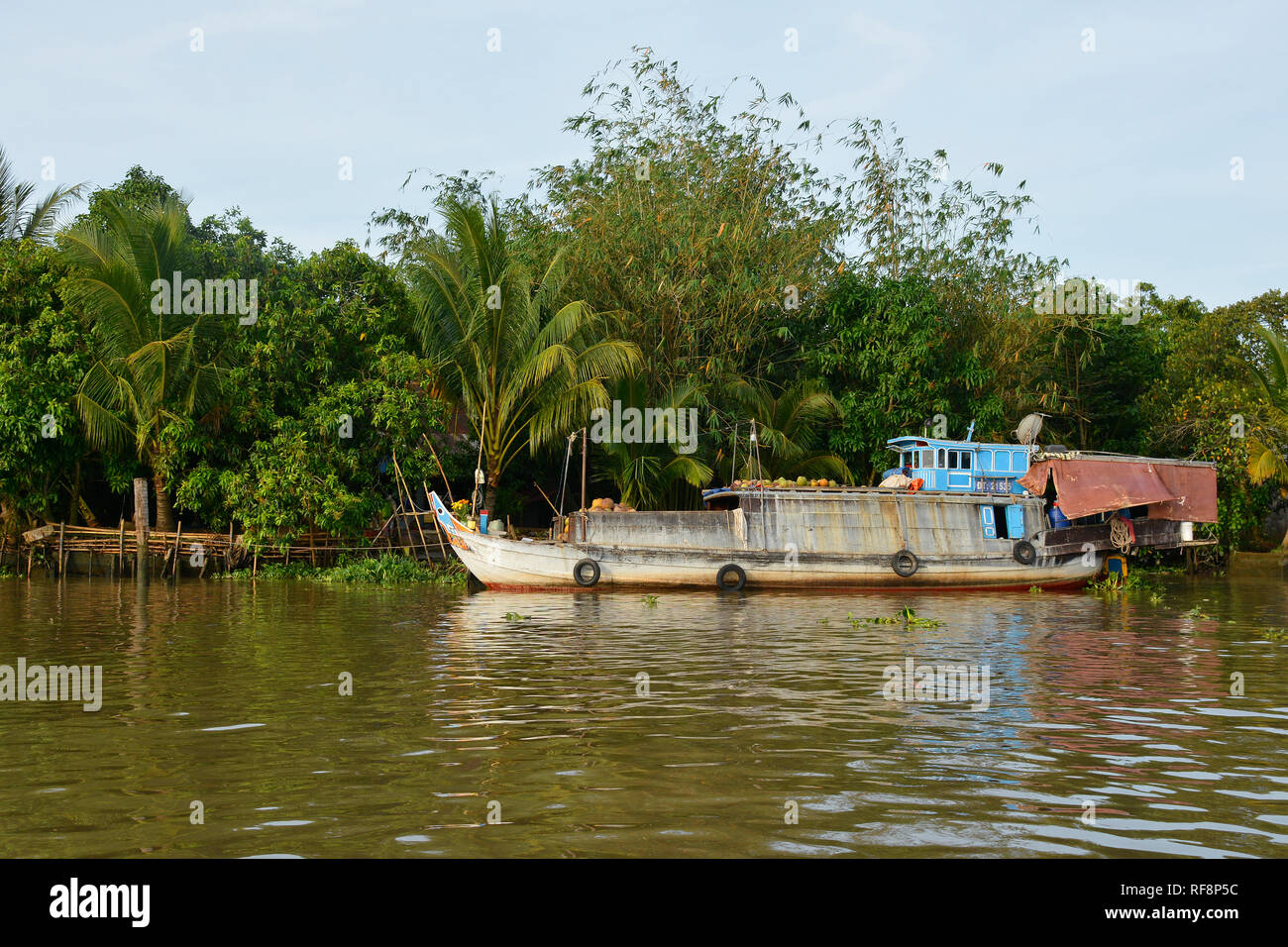 Can Tho, Vietnam - December 31st 2017. An old wooden full of vegetables is moored outside a house in the Mekong Delta following the morning's floating Stock Photo