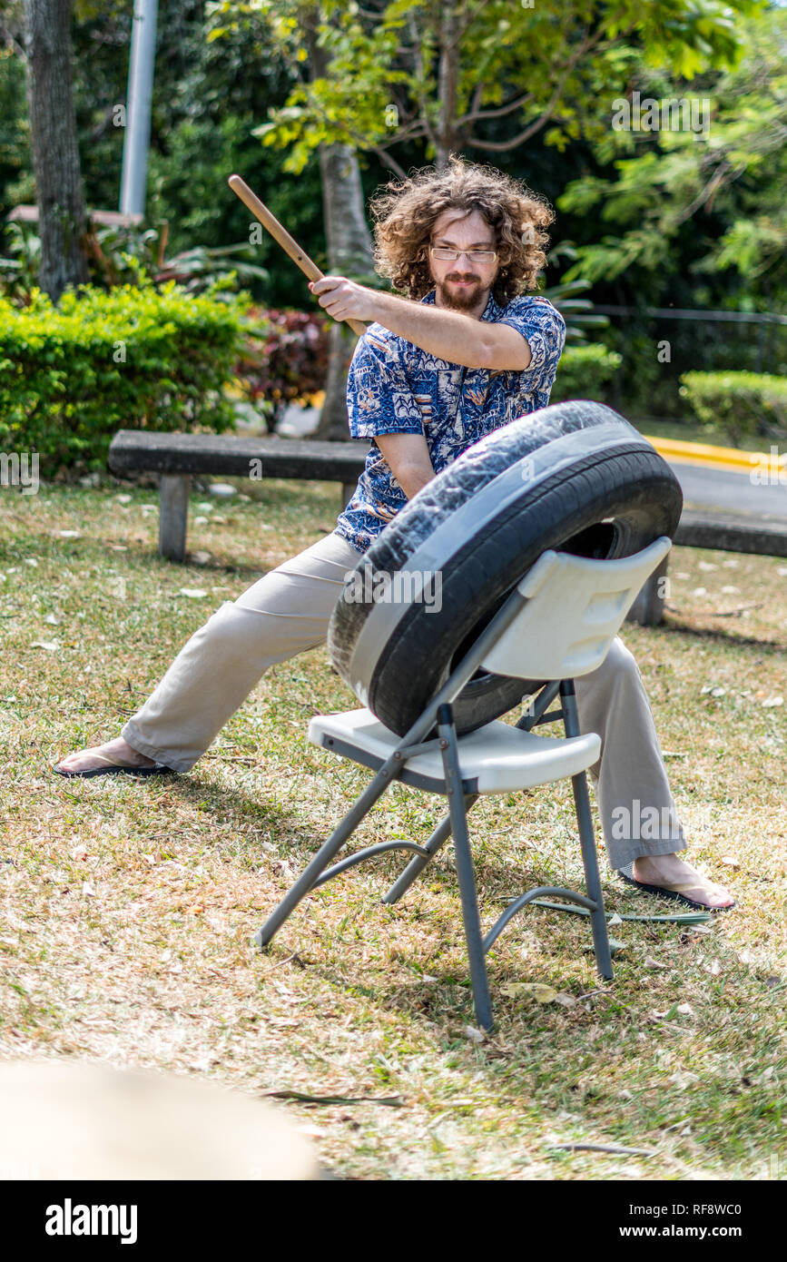 A man with curly hair is playing a Japanese taiko drum made of an old