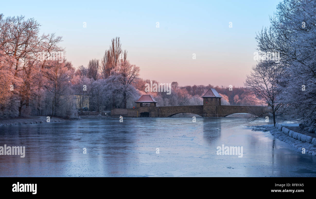 Leipzig im Frost, vereister Fluss Weiße Elster und Palmengartenwehr im roten Licht der aufgehenden Sonne Stock Photo