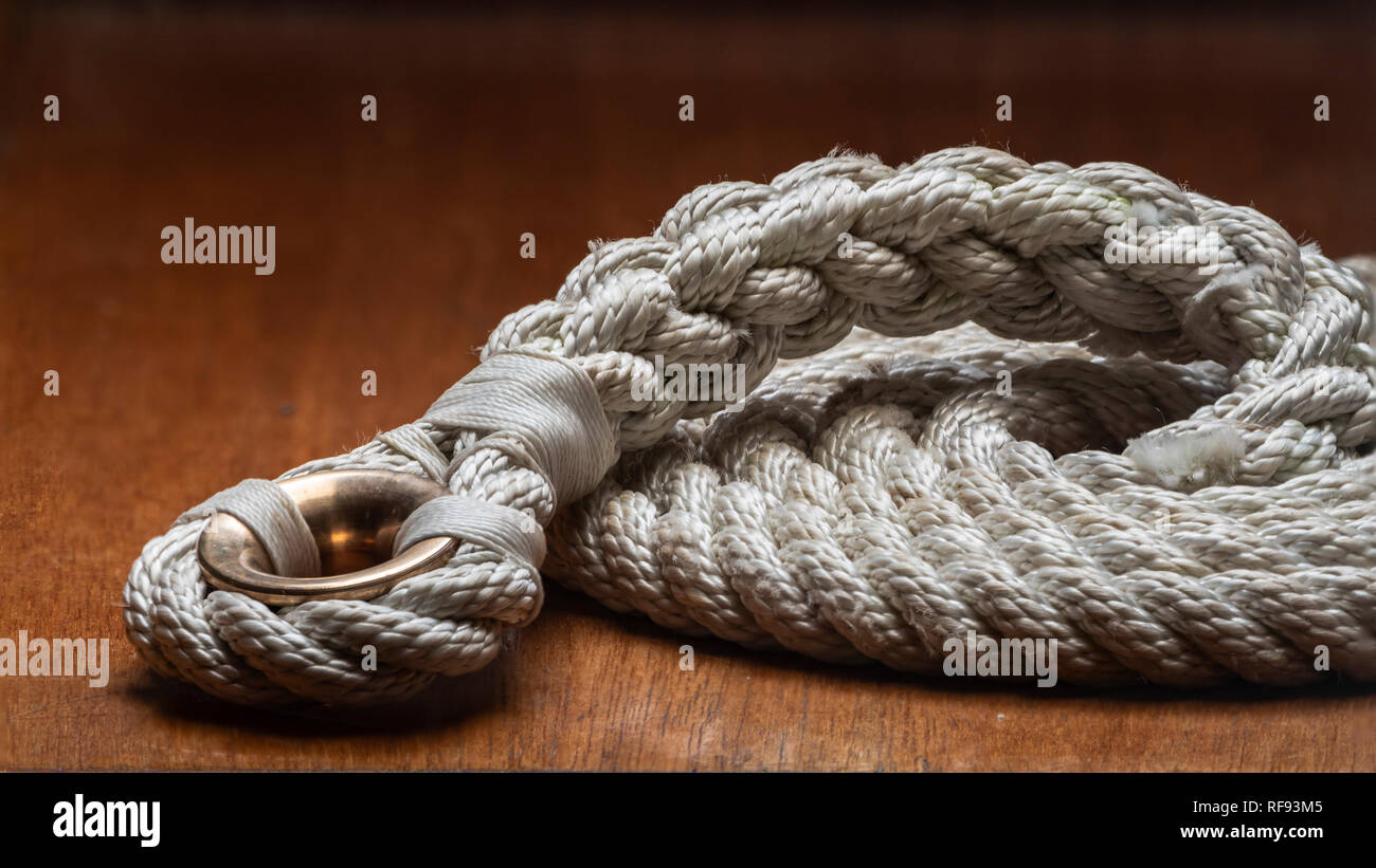 Rope with splice and bronze round thimble (low friction ring) on wooden background. Stock Photo