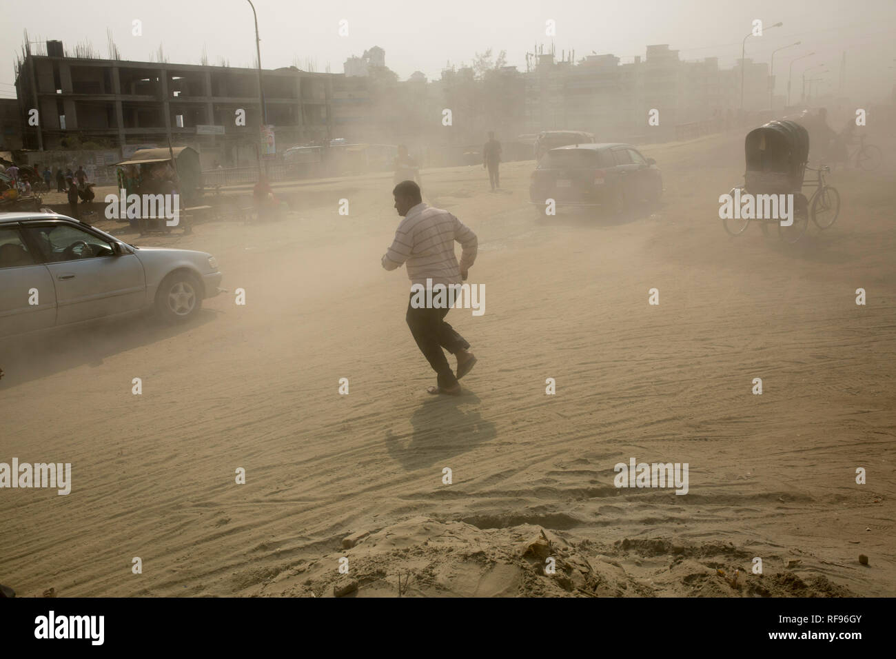 DHAKA, BANGLADESH - JANUARY 23 : Dust pollution reaches an alarming stage in Dhaka and many deaths as well as several million cases of illness occur every year due to the poor air quality in Dhaka, Bangladesh on January 23, 2019.   Dust kicked up by vehicles traveling on roads may make up 33% of air pollution. Road dust consists of deposits of vehicle exhausts and industrial exhausts, particles from tire and brake wear, dust from paved roads or potholes, and dust from construction sites. Road dust is a significant source contributing to the generation and release of particulate matter into the Stock Photo