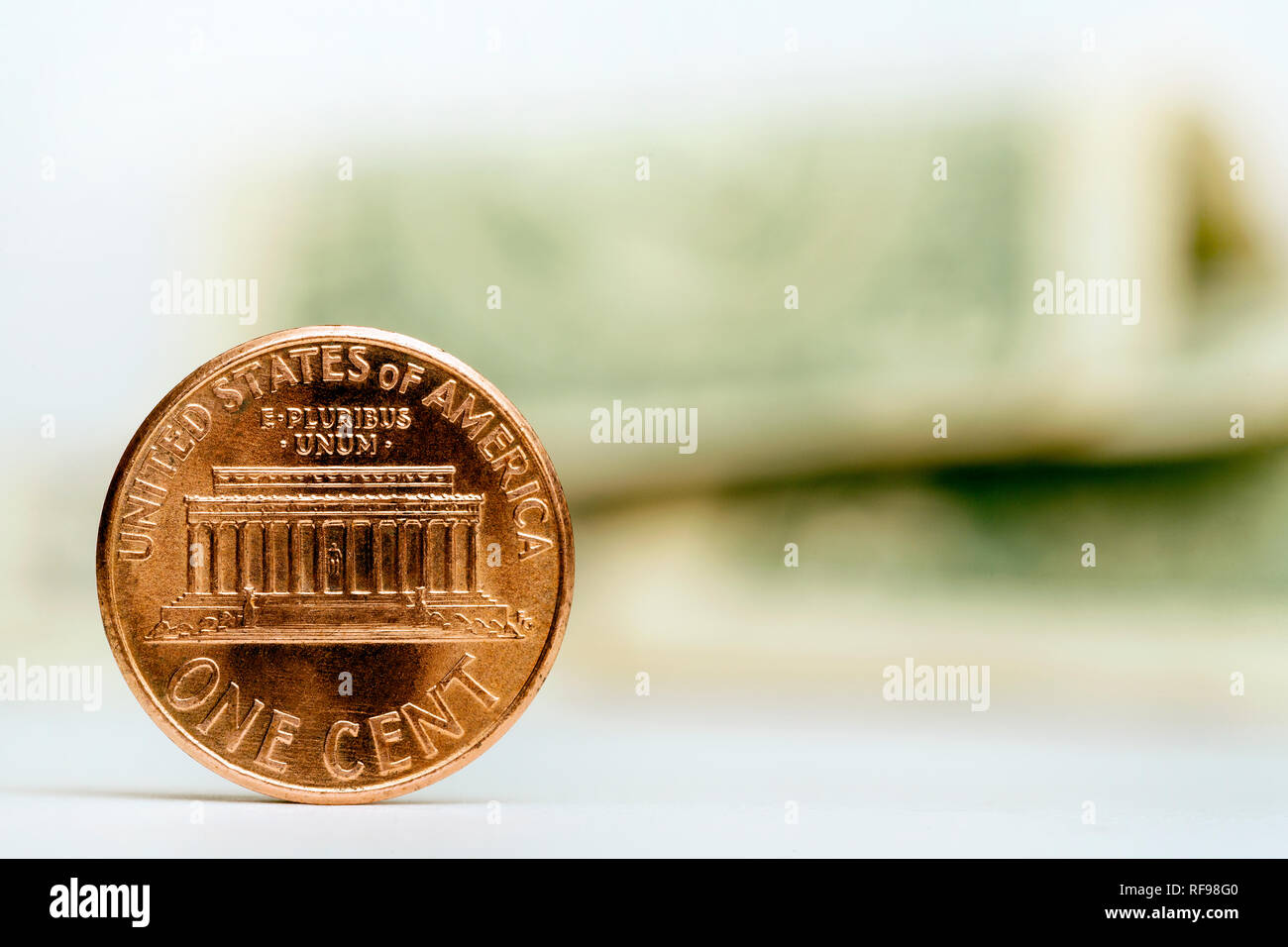 Close up of one cent coin with American dollar notes on the background Stock Photo