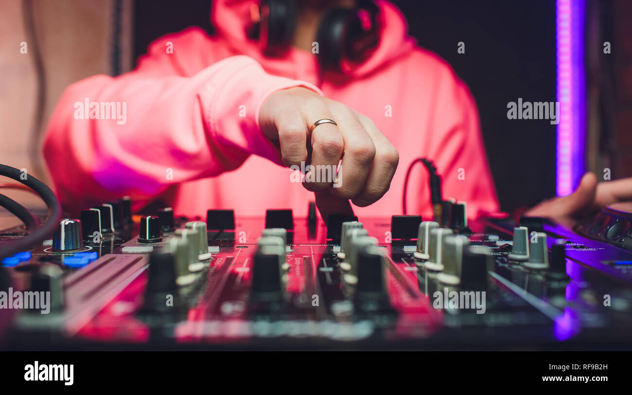 Hands of DJ mix tracks on digital turntable and software on laptop with