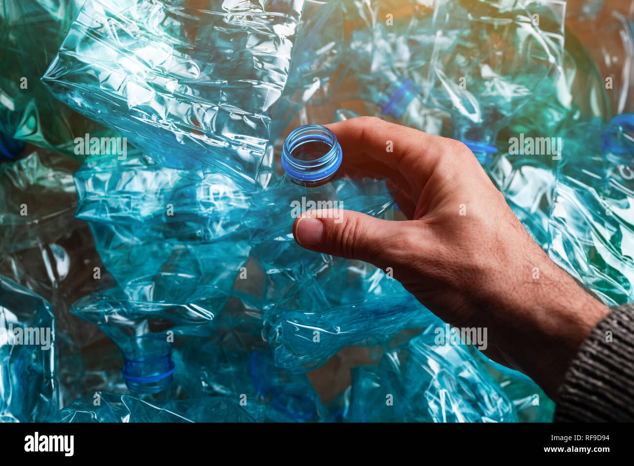 Hand among crushed plastic bottles, environmental damage concept Stock