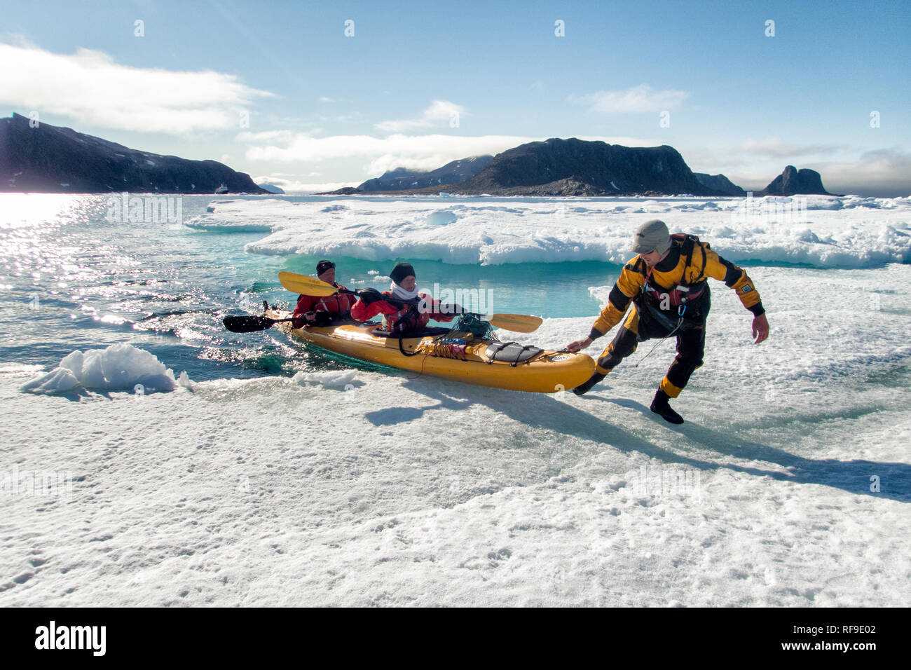 Kayaking Tourists Arctic Landscape Svalbard Norway // SVALBARD, Norway — Kayaking tourists explore the icy waters and pristine landscapes of the Arctic region surrounding Svalbard. This unique and adventurous form of tourism offers an up-close experience with the Arctic environment, showcasing the region's breathtaking beauty and fragile ecosystems. Stock Photo