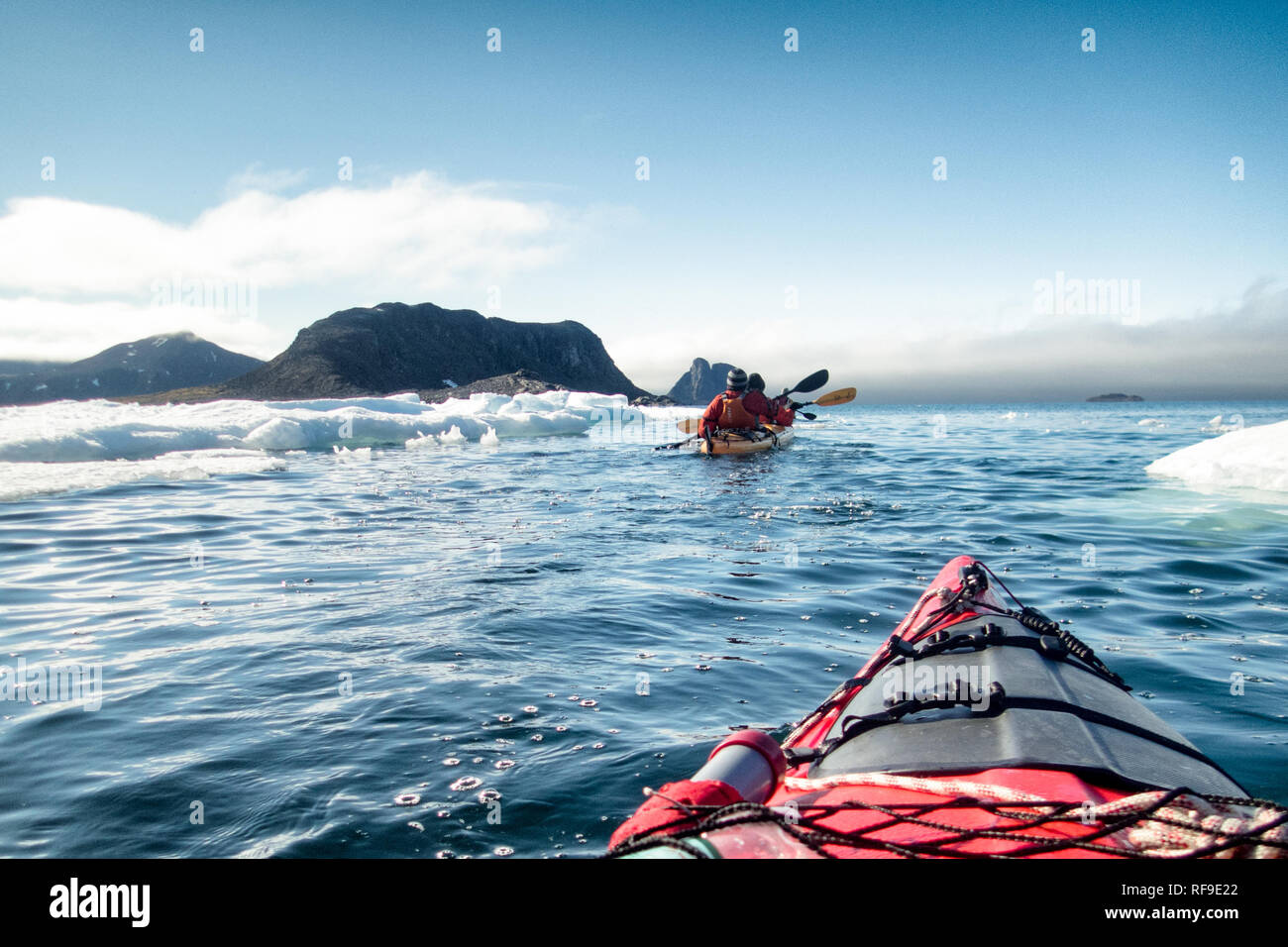Kayaking Tourists Arctic Landscape Svalbard Norway // SVALBARD, Norway — Kayaking tourists explore the icy waters and pristine landscapes of the Arctic region surrounding Svalbard. This unique and adventurous form of tourism offers an up-close experience with the Arctic environment, showcasing the region's breathtaking beauty and fragile ecosystems. Stock Photo