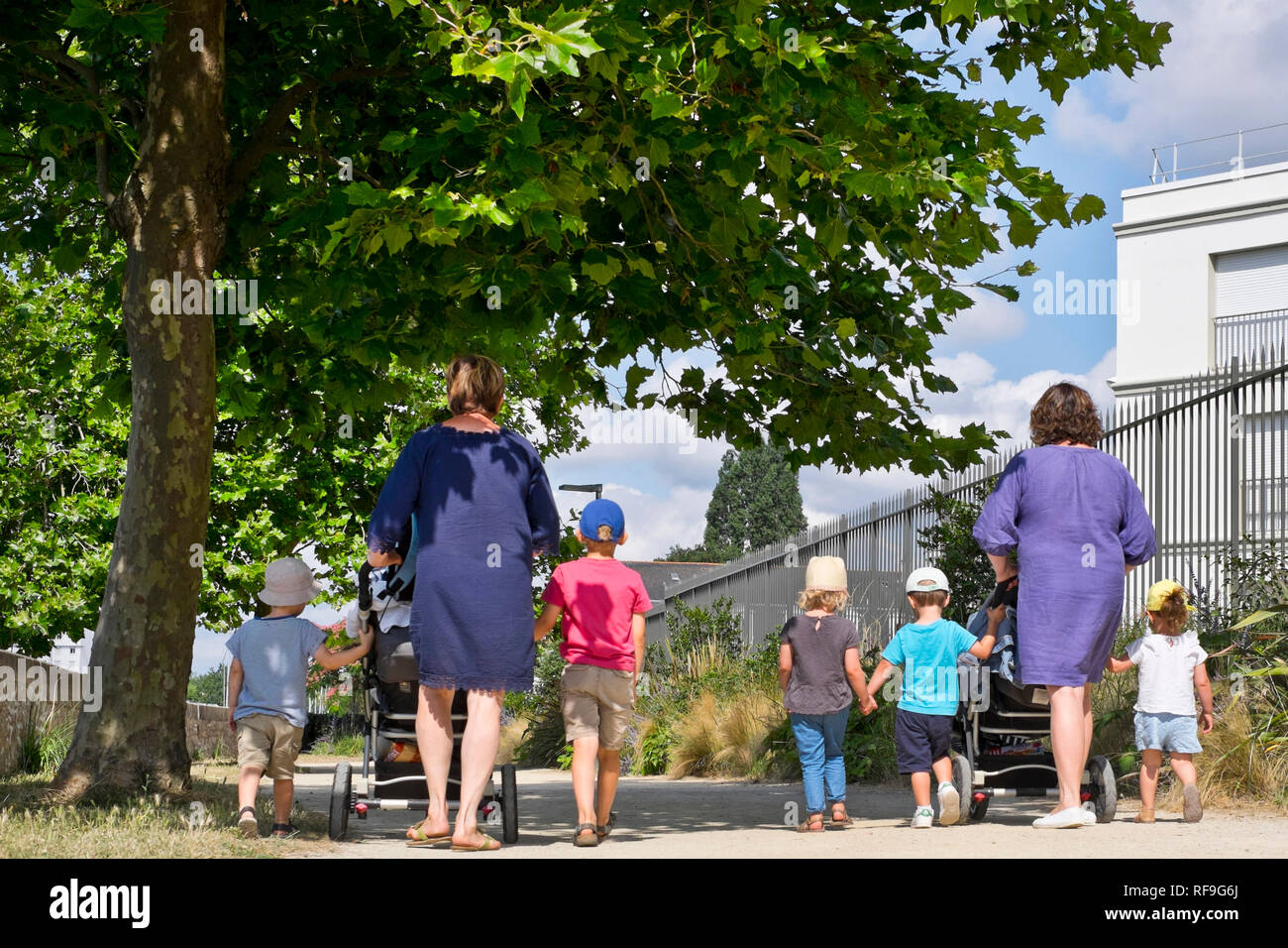 Child care: childminders and children out for a stroll. Two childminders with stroller and children having a walk *** Local Caption *** Stock Photo