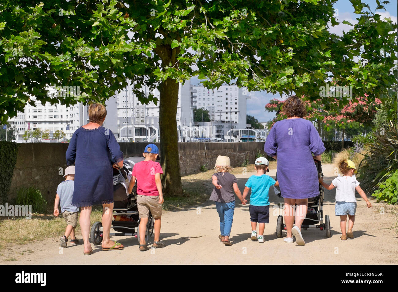 Child care: childminders and children out for a stroll. Two childminders with stroller and children having a walk *** Local Caption *** Stock Photo