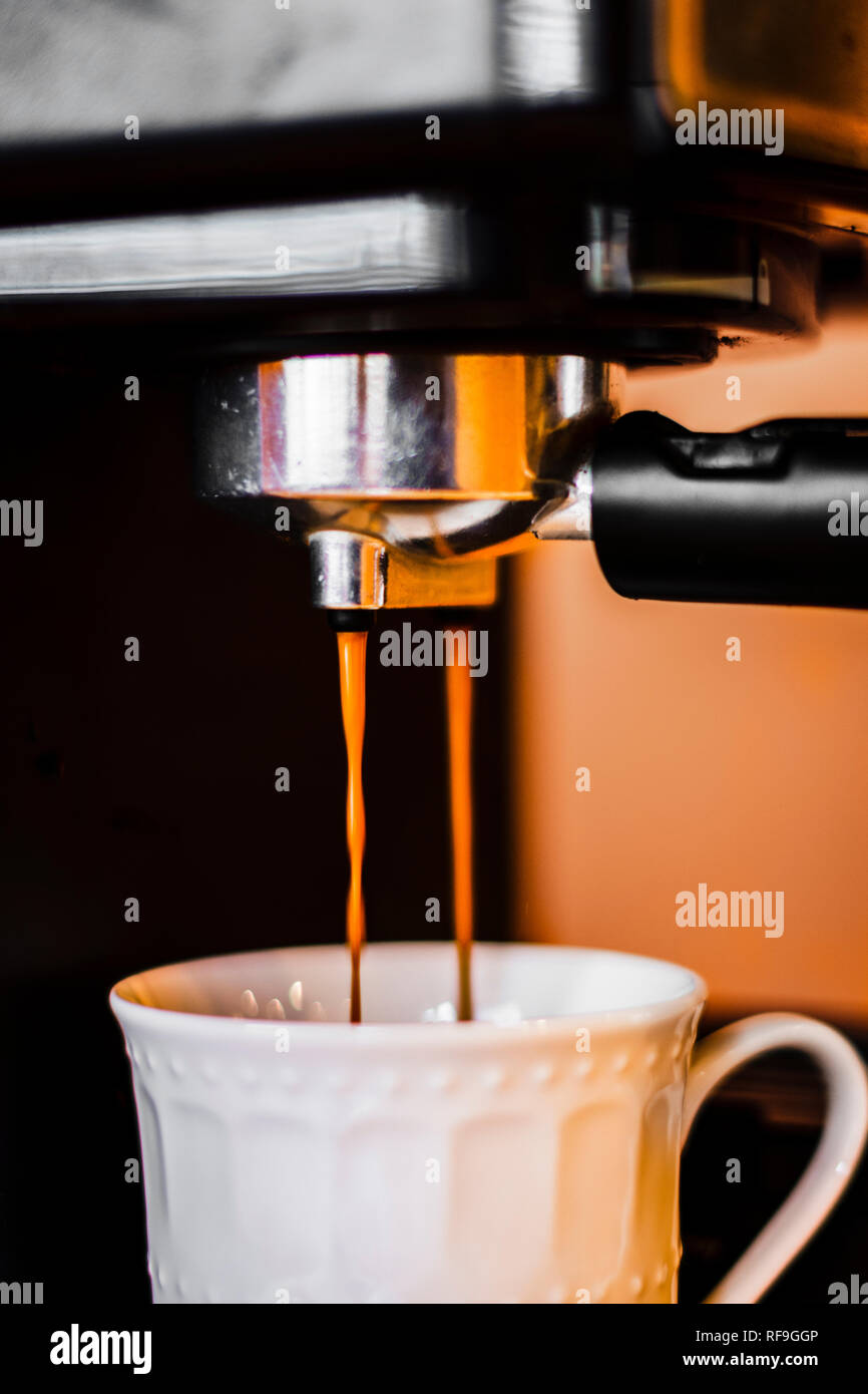 Shot of an espresso coffee being made by an espresso machine, pouring down into a coffee cup. Stock Photo