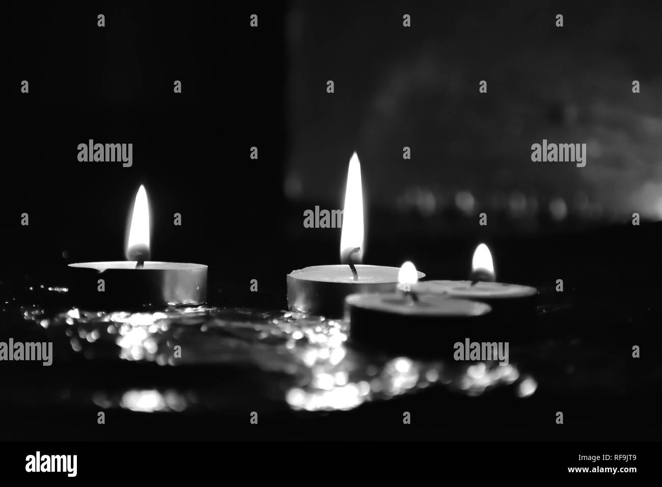 Beautiful tea candle light glowing in darkness, black & white Stock