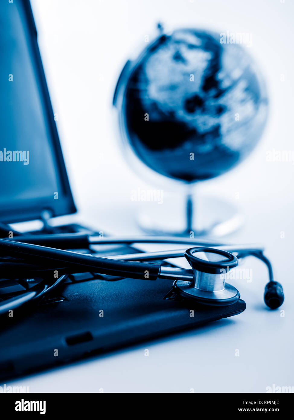 Glass globe and stethoscope on a computer keyboard.blue toned images ...