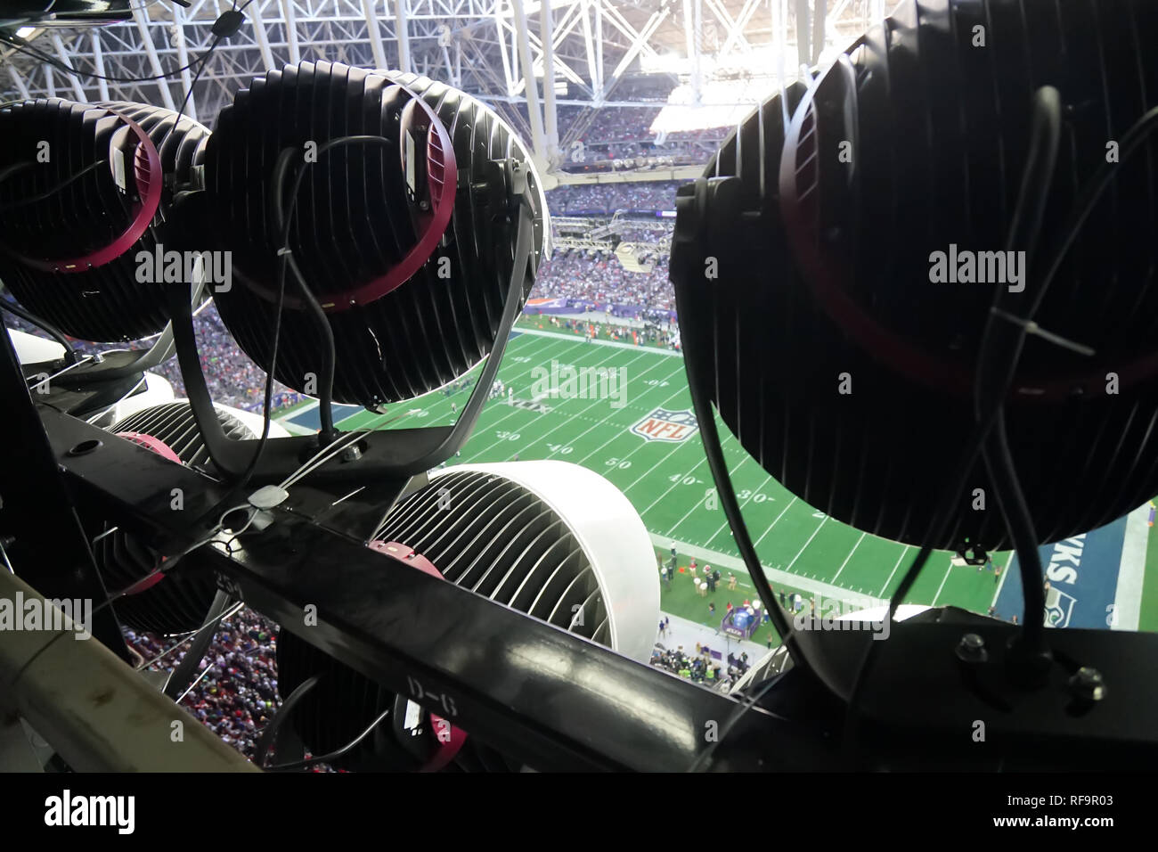 A group of stadium light illuminate a football field. Stock Photo
