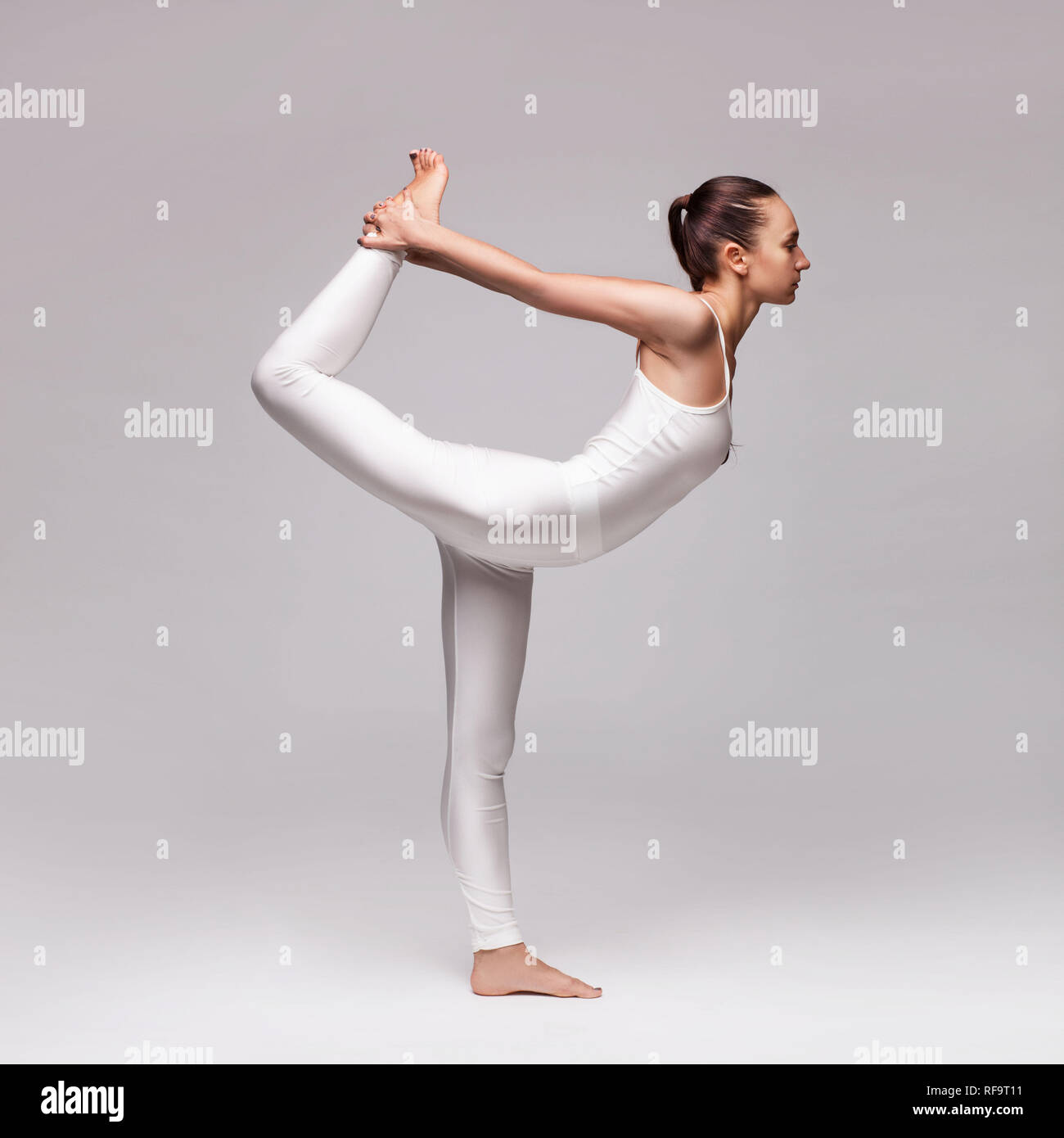 young beautiful woman yoga posing isolated over grey studio background ...