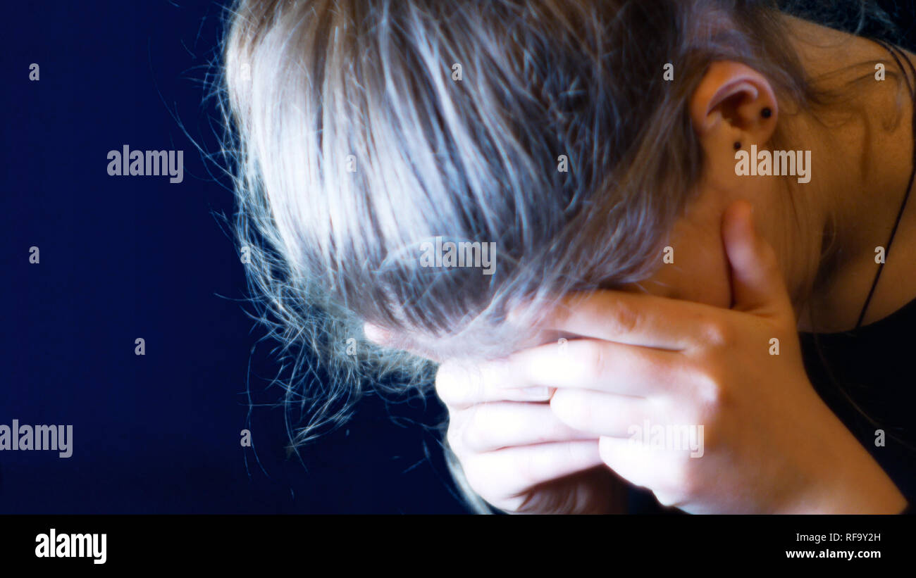 teenage girl holds her head in her hands because she is very desperate ...