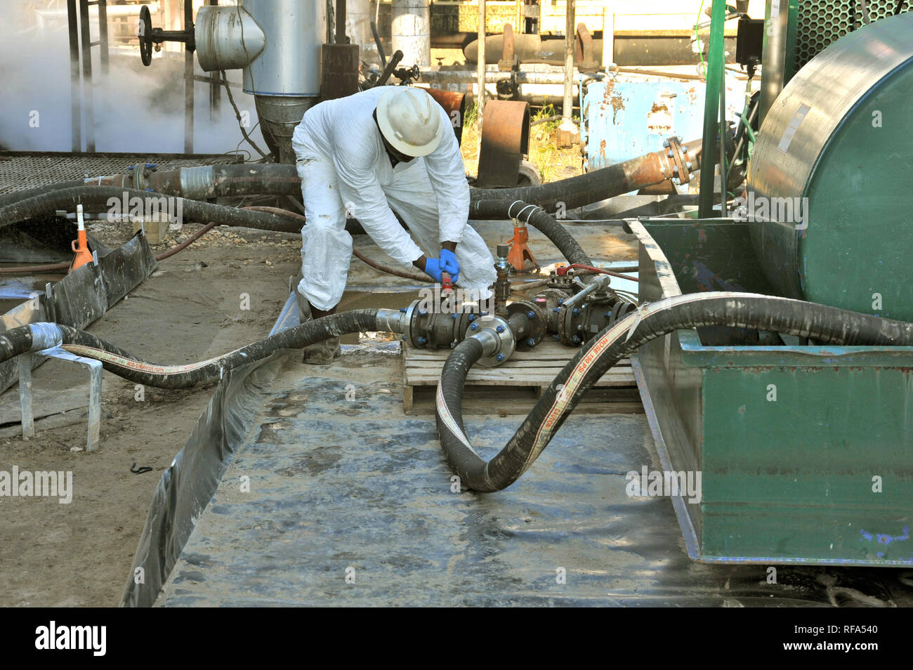 Refinery technician transferring petroleum product Stock Photo
