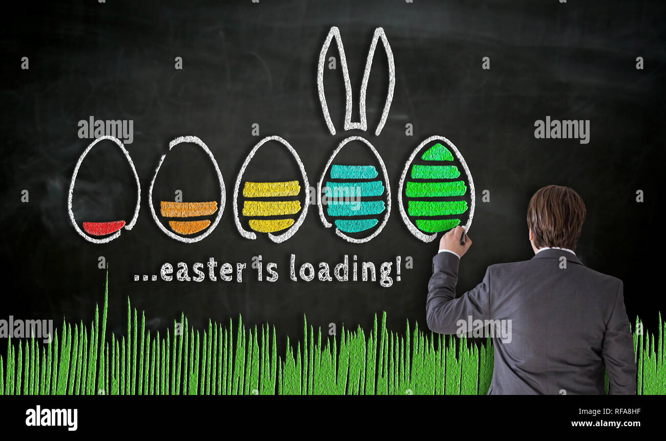 Businessman paints with chalk Easter concept on blackboard. Stock Photo