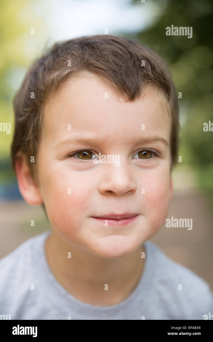 Closeup portrait of a smiling freckled boy with dark hair and brown eyes outdoors Stock Photo