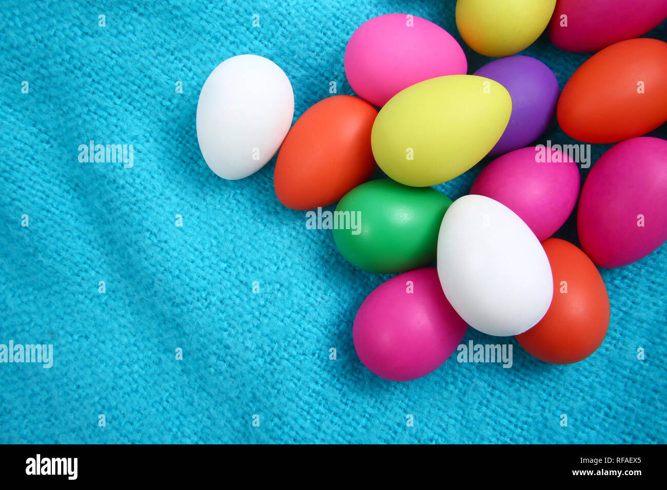 Multi colored easter eggs against a bright blue wool blanket background. Stock Photo