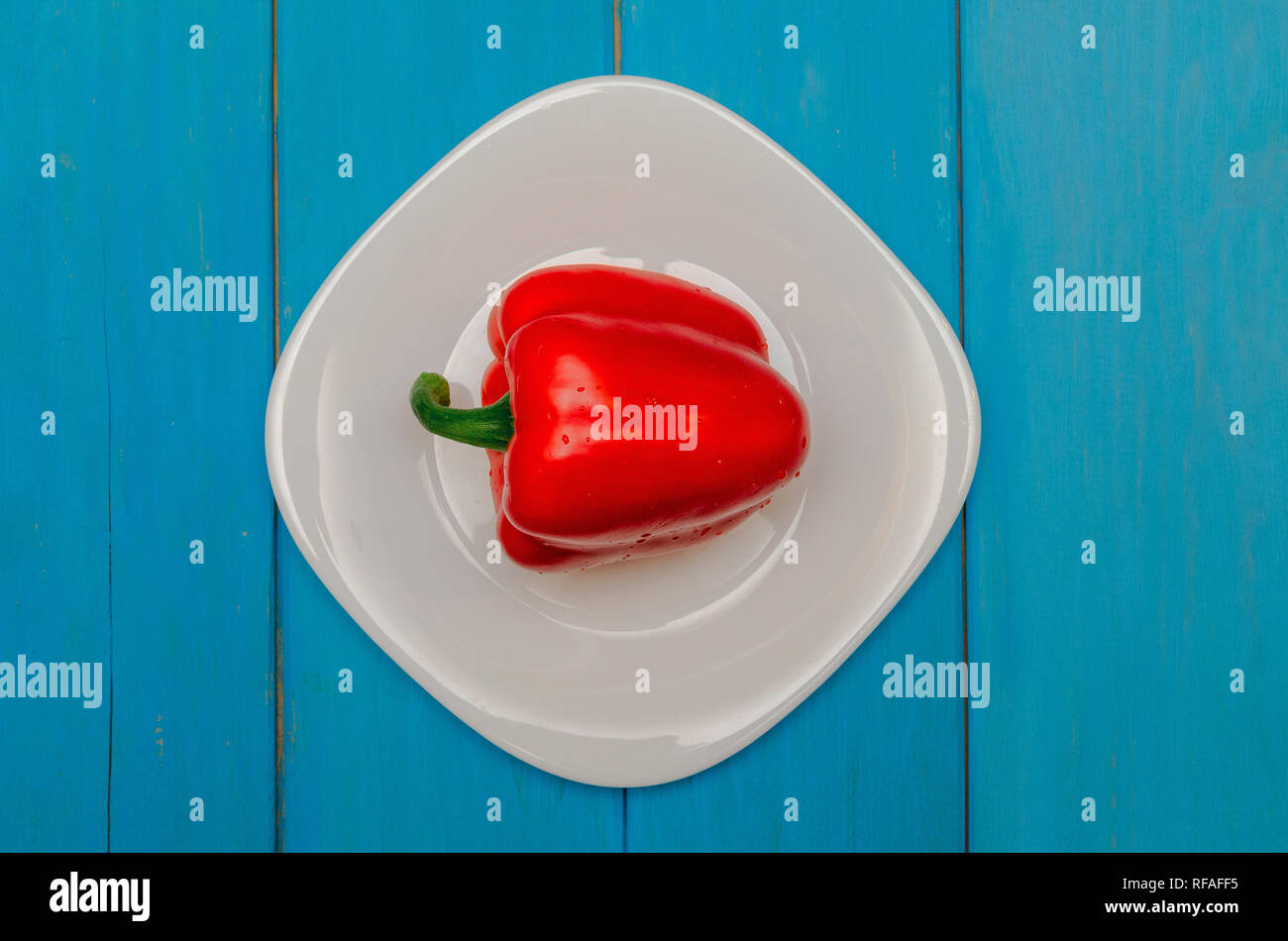 Bulgarian red pepper on a white plate. Wooden blue background. The ...