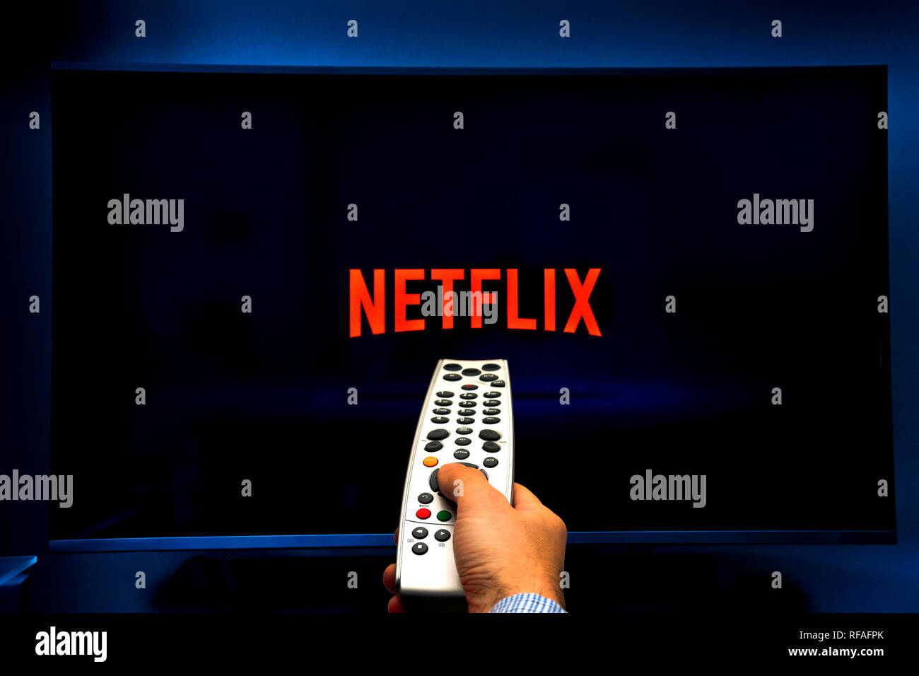 male hand holding a remote control and watching Netflix Stock Photo