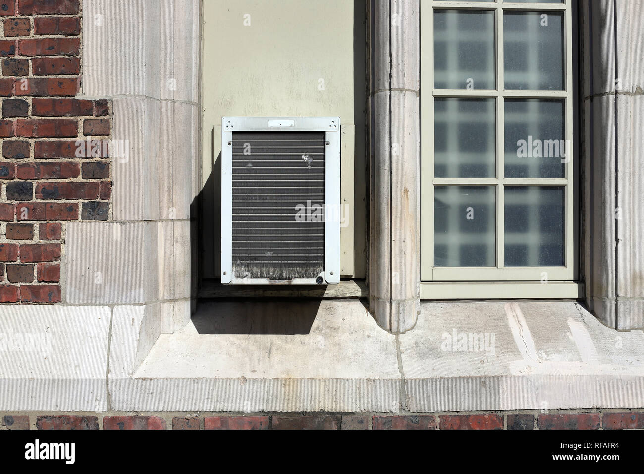 Window Air Conditioner unit on old brick building Stock Photo
