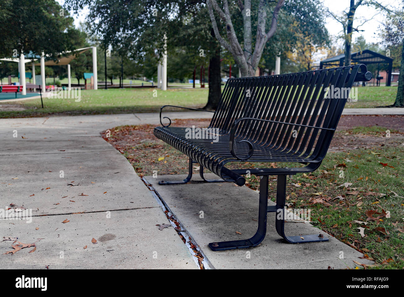 Empty black bench seat at playground park with equipment on sunny day Stock Photo