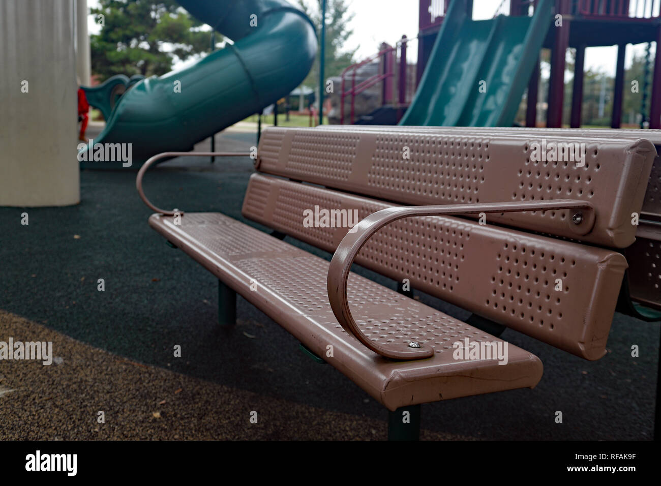 Empty bench seat at playground park with equipment on sunny day Stock Photo