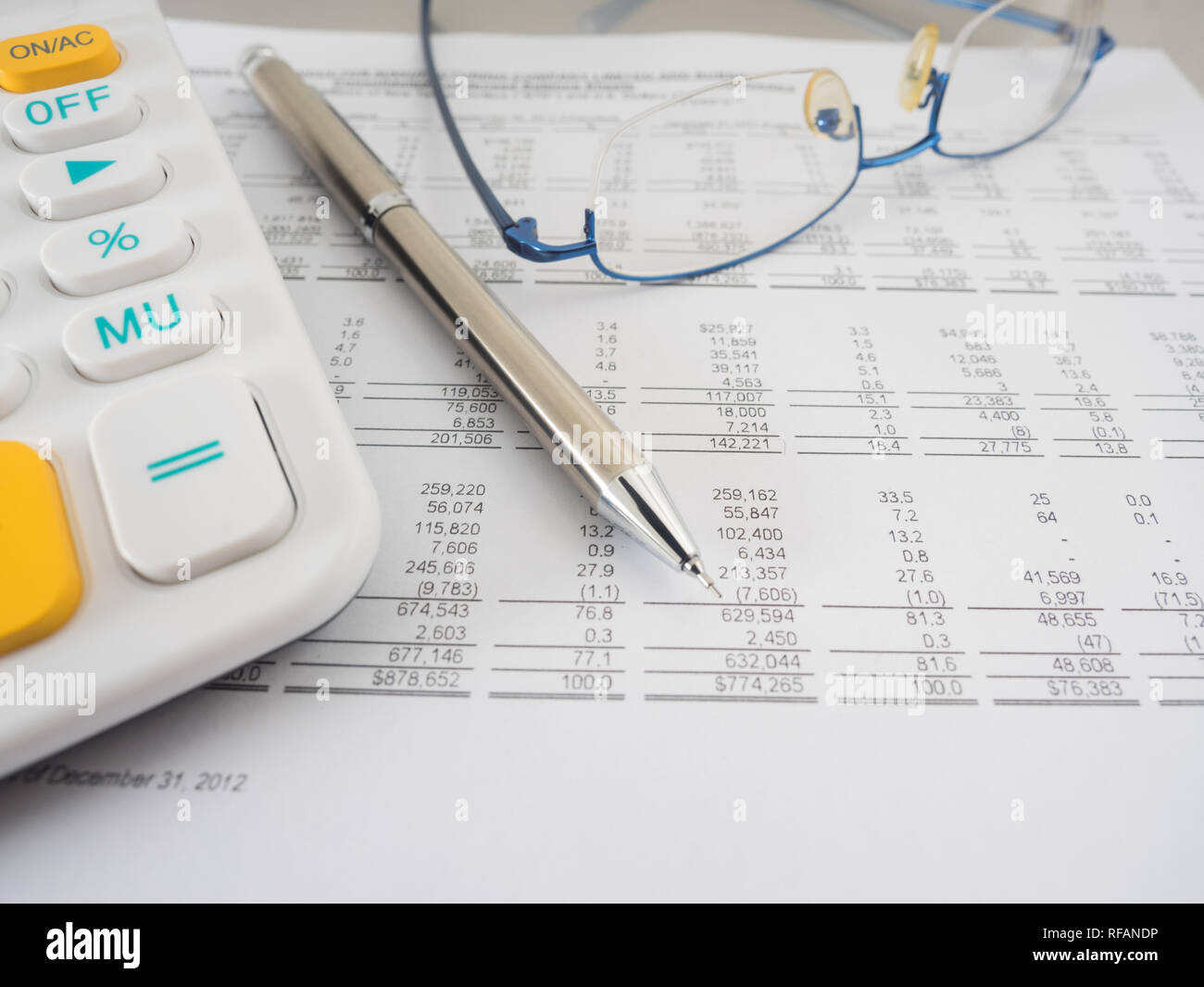 A close-up shot of a calculator. A printed balance sheet and a pen are ...