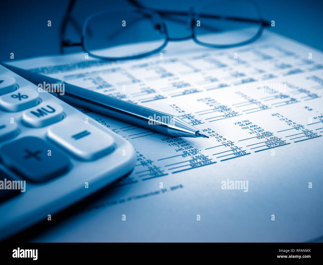 A closeup shot of a calculator. A printed balance sheet and a pen are