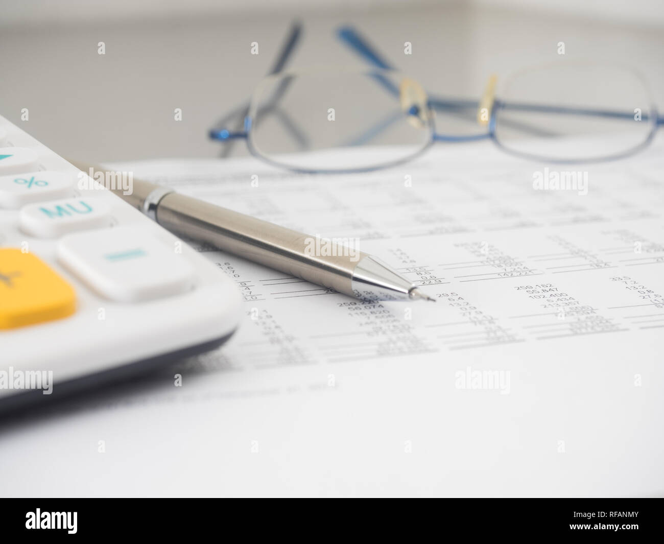 A close-up shot of a calculator. A printed balance sheet and a pen are ...