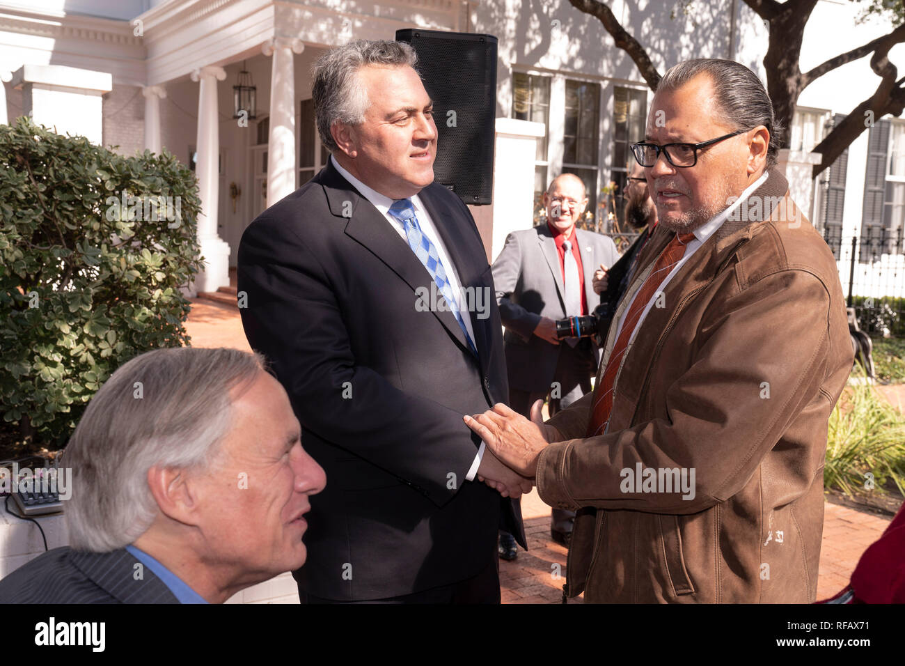 Joe Hockey, center, Australia's ambassador to the United States, shakes hands with Texas state Sen. Jose Rodriguez as Texas Gov. Greg Abbott looks on during the Great Mates Australia-Texas Barbecue at the Governor's Mansion. Abbott and Hockey worked to strengthen ties between the allies discussing agriculture and high tech before eating Australian Vegemite burnt ends and HeartBrand Akaushi beef. Stock Photo
