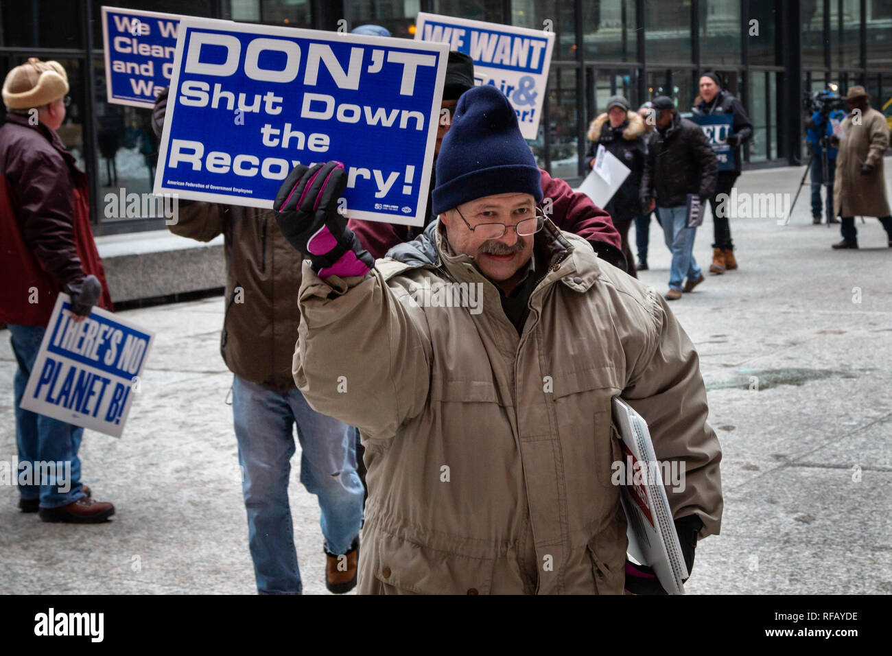 Chicago, Illinois, USA. 24th January, 2019. For the third time in just over two weeks furloughed government workers gathered at noon under the Calder Flamingo in Chicago' s frigid Federal Plaza and demanded that congress and President Trump put an end to the government shut down. While a light snow began to fall, and after listening to speeches of support from union leaders representing the AFGE, the NTEU and other concerned organizations, the effected workers marched around the plaza with their signs. Credit: Matthew Kaplan/Alamy Live News Stock Photo