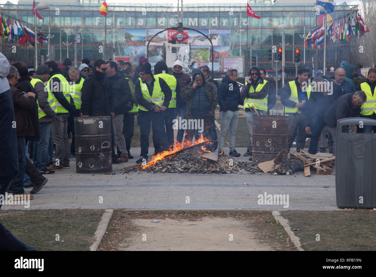 Madrid, Spain. 24th January, 2019. Protesters wearing yellow vests set a bonfire during a taxi driver  strike near Fitur, the Tourism Fair that is to take place this week at IFEMA in Madrid. The drivers are demanding more stringent regulation for rental vehicles with drivers (VTC), who use Uber or Cabify applications. Credit: SOPA Images Limited/Alamy Live News Stock Photo