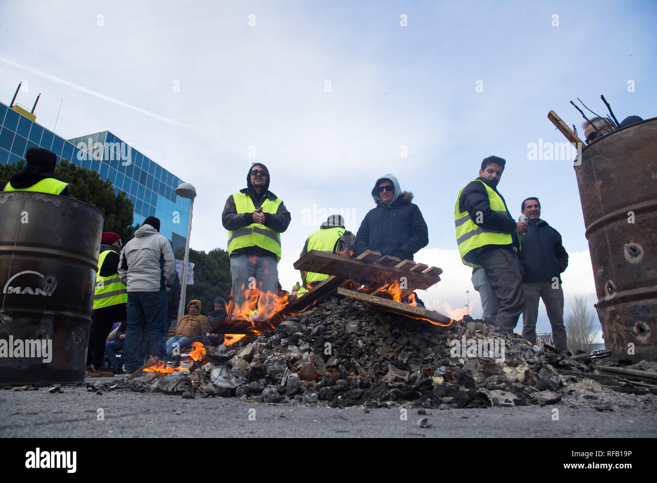 Madrid, Spain. 24th January, 2019. Yellow vests protesters are seen setting a bonfire during a taxi driver strike near Fitur, the Tourism Fair that is to take place this week at IFEMA in Madrid. The drivers are demanding more stringent regulation for rental vehicles with drivers (VTC), who use Uber or Cabify applications. Credit: SOPA Images Limited/Alamy Live News Stock Photo