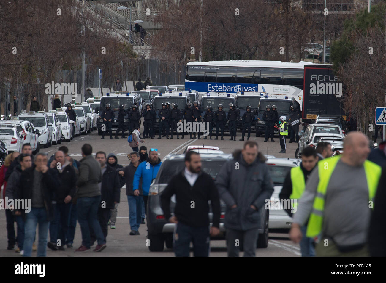 Madrid, Spain. 24th January, 2019. Police standing guard during a taxi driver  strike near Fitur, the Tourism Fair that is to take place this week at IFEMA in Madrid. The drivers are demanding more stringent regulation for rental vehicles with drivers (VTC), who use Uber or Cabify applications. Credit: SOPA Images Limited/Alamy Live News Stock Photo