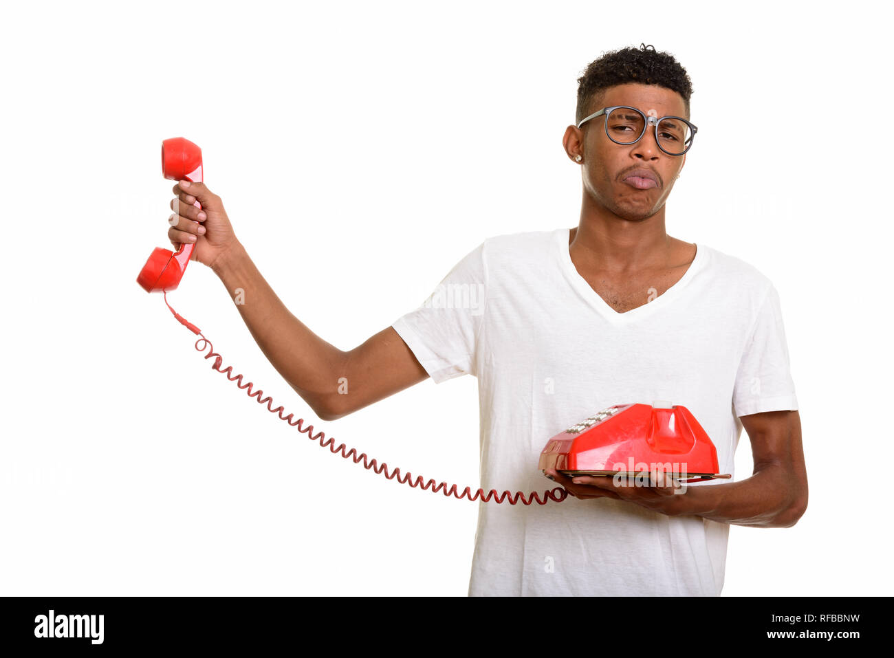 Young handsome African man looking annoyed while holding telepho Stock Photo