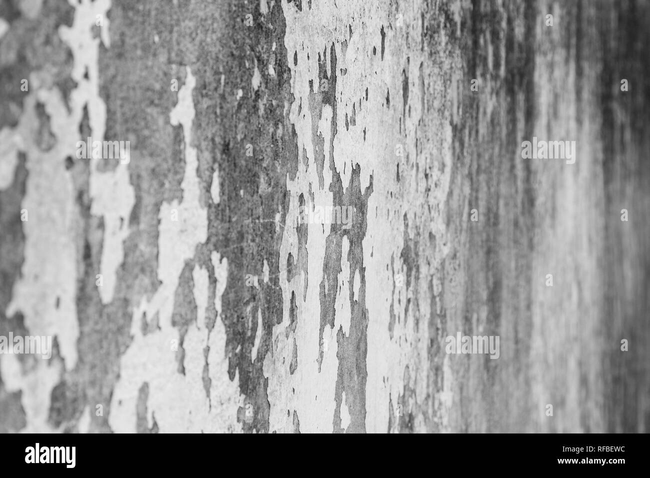 Side view of a weathered and old gray concrete wall in black and white. Plaster is partly peeled off. Selective focus, shallow depth of field. Stock Photo