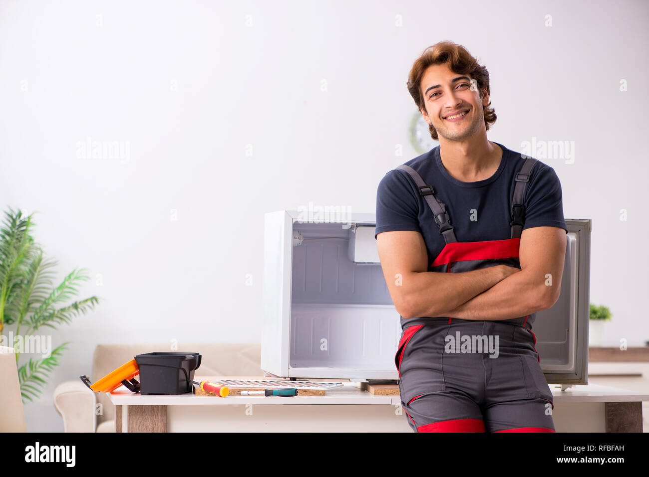 Young handsome contractor repairing fridge Stock Photo