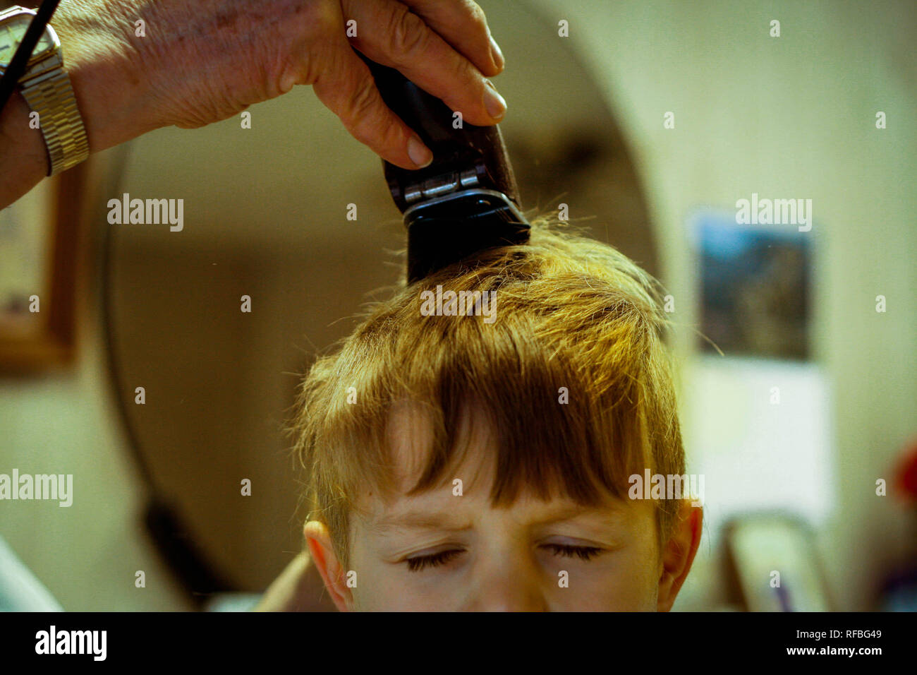 A young boy has his hair cut at a smalltown babershop.. Stock Photo