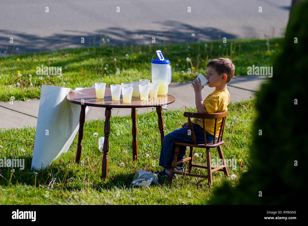 A 5-year old boy sits at a lemonade stand with cups and a pitcher of  lemonade Stock Photo - Alamy