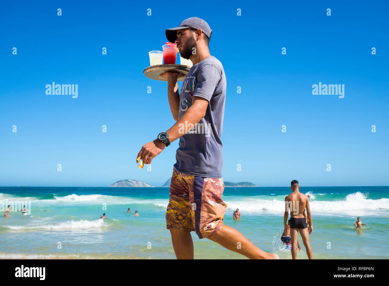 RIO DE JANEIRO - MARCH, 2018: An unlicensed beach vendor selling homemade caipirinha cocktails looks for potential customers on Ipanema Beach. Stock Photo