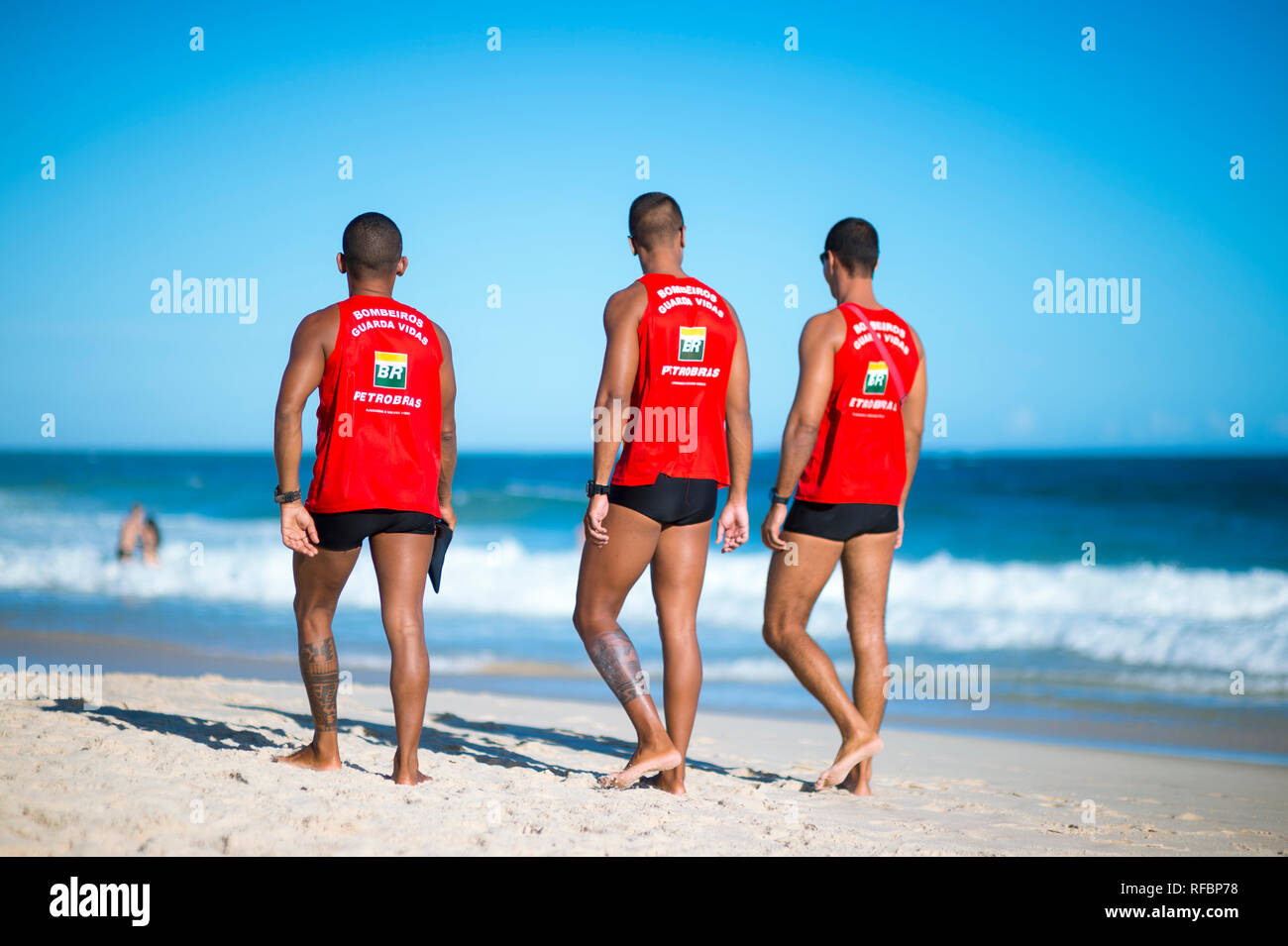 RIO DE JANEIRO - MARCH, 2018: Brazilian lifeguards in uniforms sponsored by the embattled oil company Petrobras monitor heavy surf on Ipanema Beach. Stock Photo