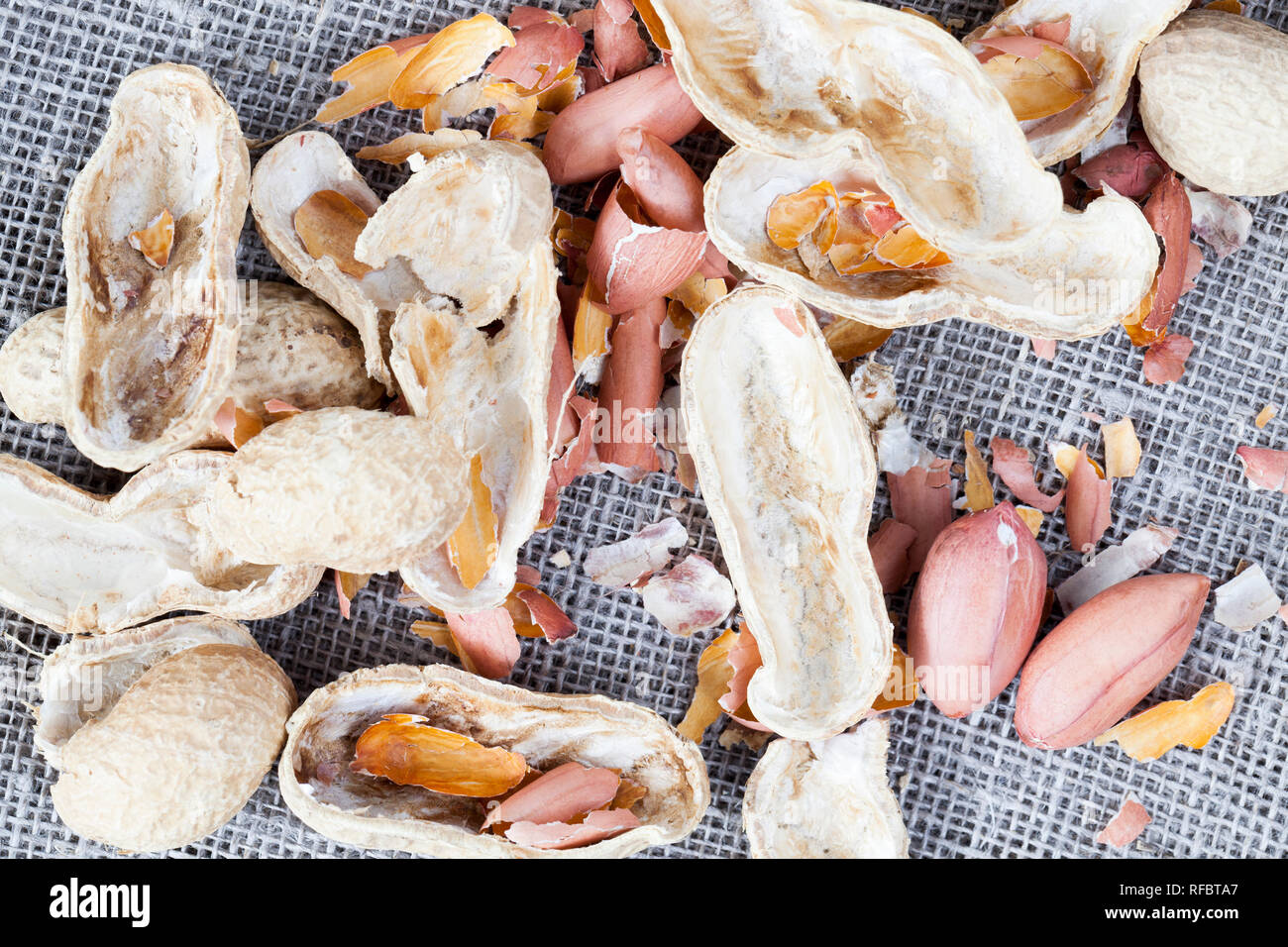broken and peeled peanuts with shells, edible part without shells and ready for ingestion, lies a linen tablecloth in the kitchen Stock Photo