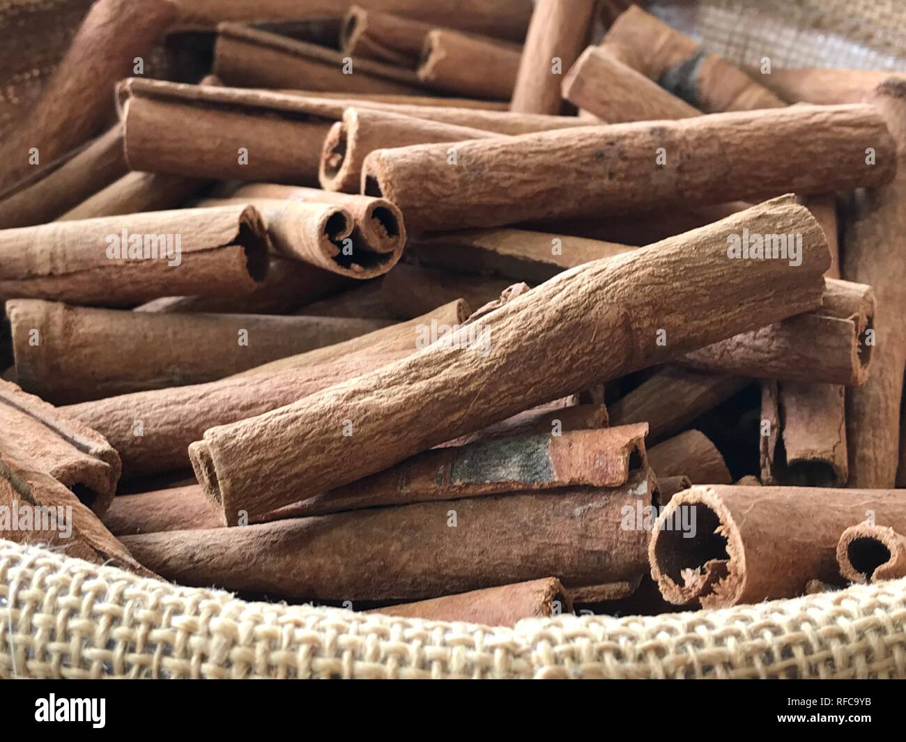 Cinnamon sticks in jute basket at the market close up brown background natural spices crop focus Stock Photo