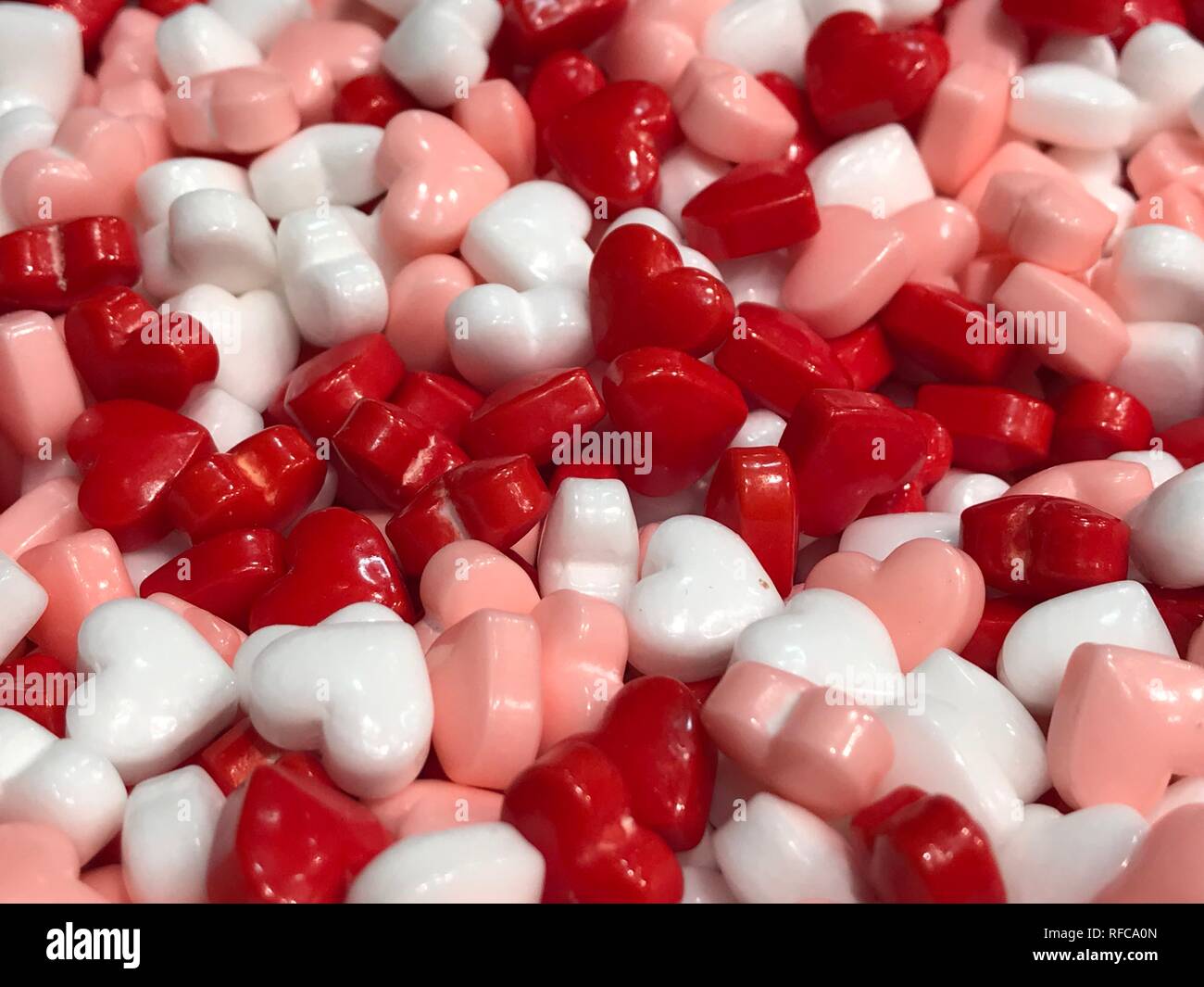 Hearts background love symbol lots of small sweet candies in a heart shape in white red and pink Stock Photo