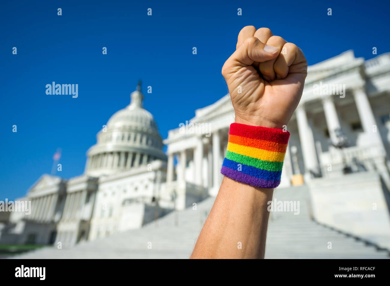 Hand wearing gay pride rainbow wristband making a power fist gesture in front of the US Capitol Building in Washington, DC, USA Stock Photo