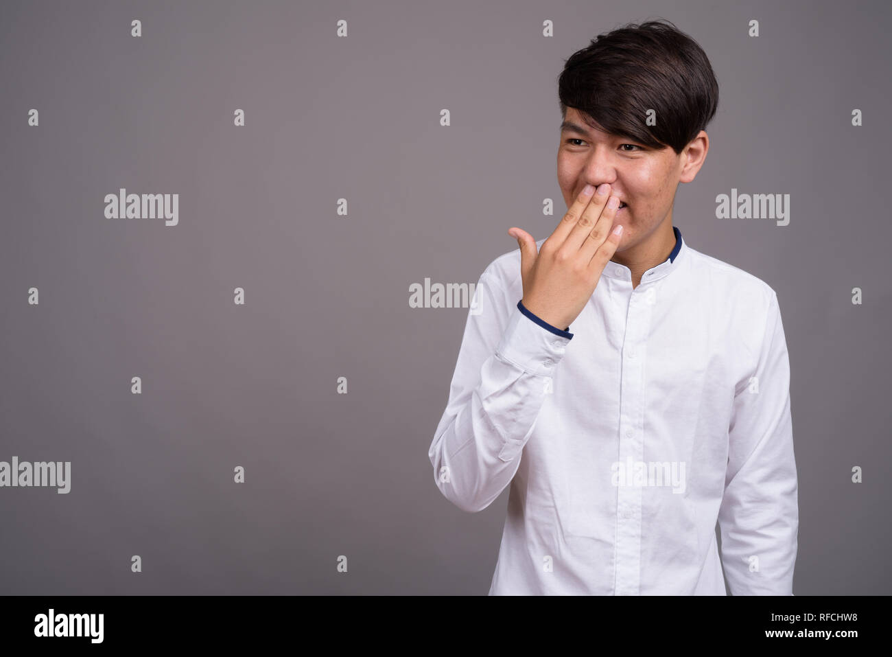 Young Asian teenage boy against gray background Stock Photo