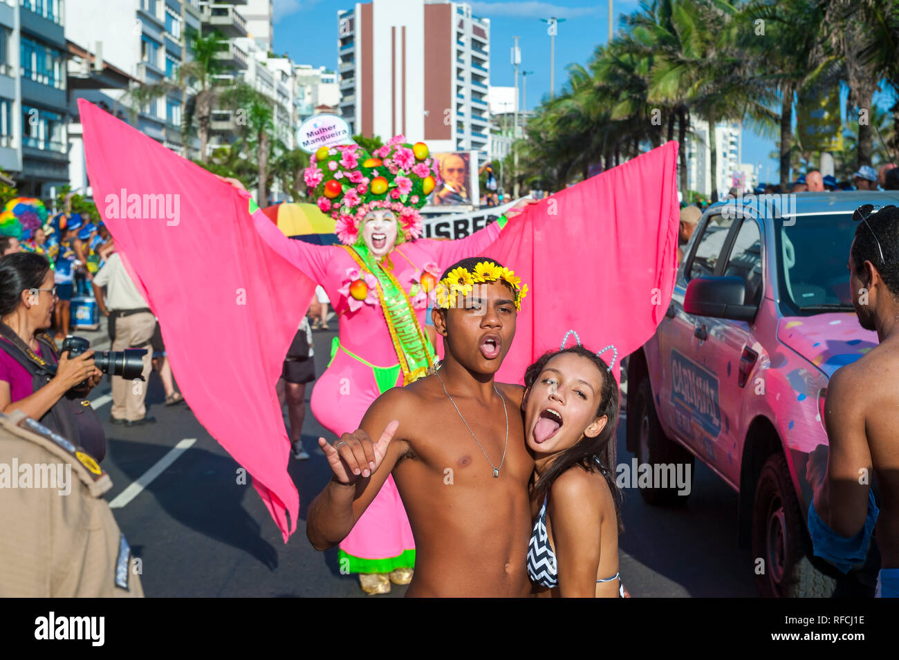 RIO DE JANEIRO - FEBRUARY 11, 2017: A Brazilian man in flamboyant pink costume photobombs a selfie of spectators at a Carnival street party in Ipanema Stock Photo