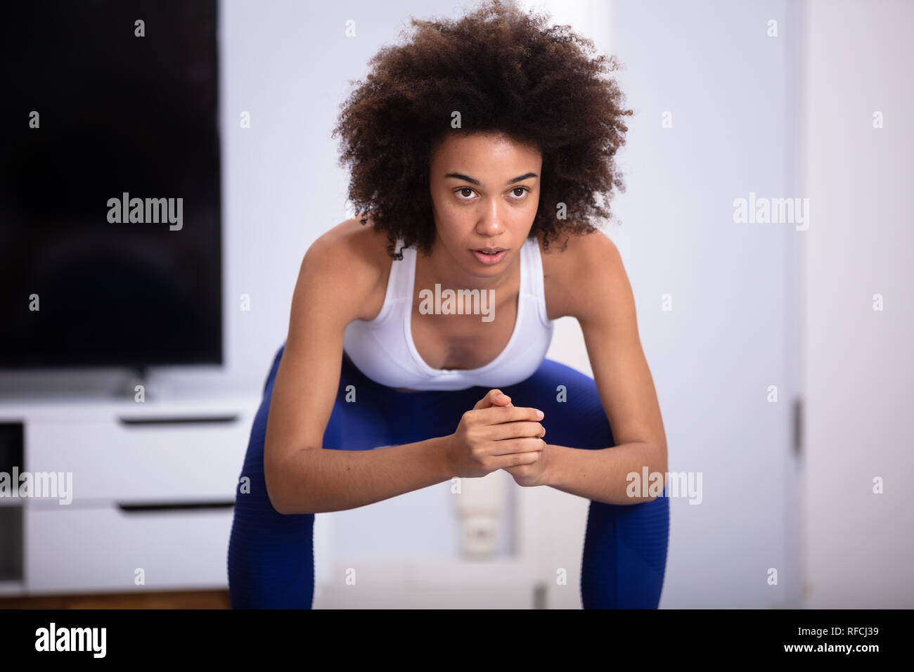 Young Woman In Fitness Wear Doing Squat Exercise At Home Stock Photo